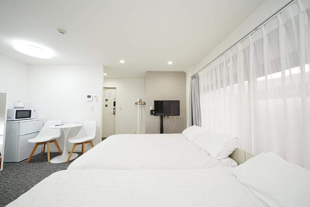 小岩 Economy stay in Tokyo の客室。白いベッド、テレビ、テーブルがある